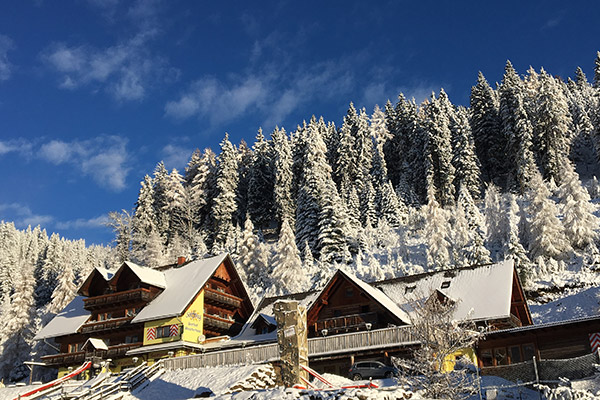 Blick auf den Gasthof Moasterhaus im Winter - verschneites Dach und im Hintergrund die verschneiten Fichten und Tannen.